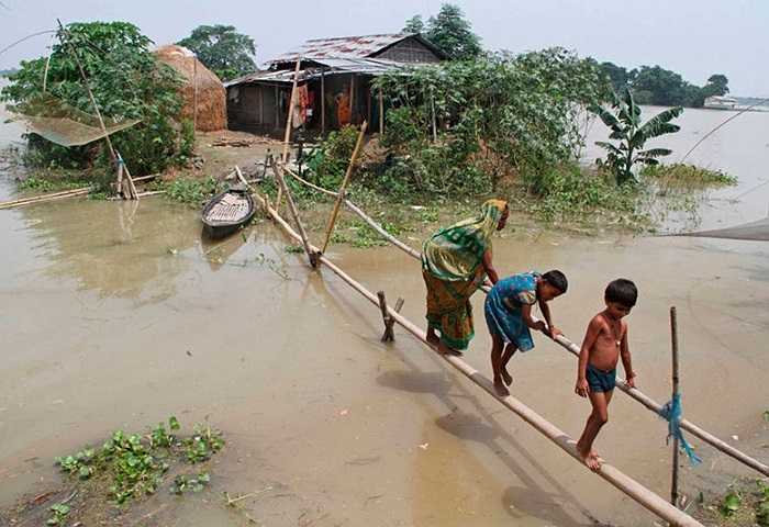 Người dân dùng cầu tre di chuyển trong cơn lũ ở bang Assam, Ấn Độ