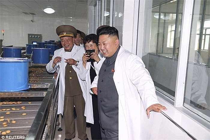 Nhà lãnh đạo tươi cười bên dây chuyên sản xuất bánh kẹo