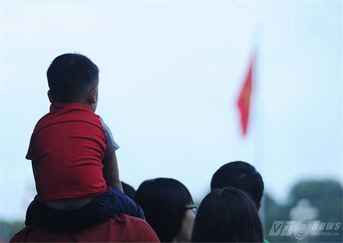 Cậu bé được bố cho lên vai để xem chào cờ rõ hơn