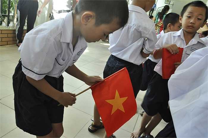 Tú Anh tự sửa lại lá cờ của mình trước giờ khai giảng. (Ảnh: Minh Chiến)
