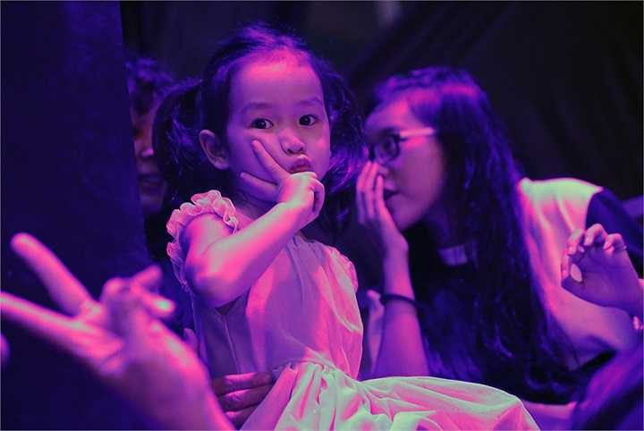 Cô bé chăm chú nhìn bố mẹ từ xa và luôn vỗ tay mỗi khi đến tiết mục có sự xuất hiện của bố mẹ