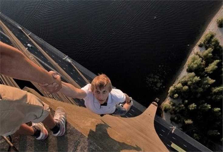 Trong ảnh, chàng trai vô tư giao tính mạng của mình vào tay một người bạn trên độ cao hơn 115 m.