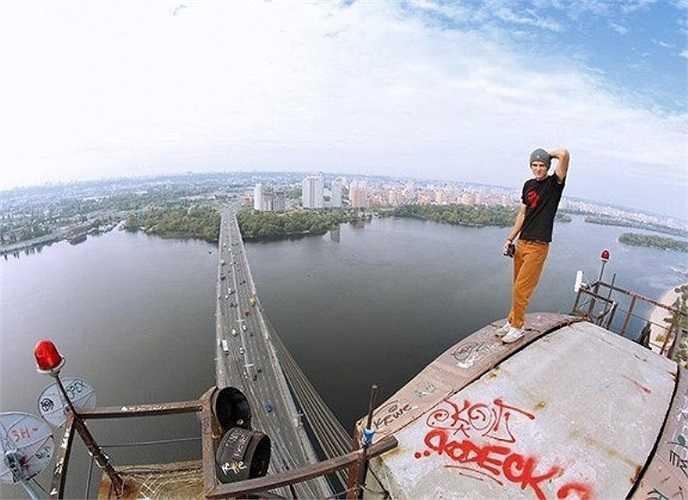 Chàng trai tạo dáng như người mẫu trên nóc một tòa nhà có phần cũ kĩ.