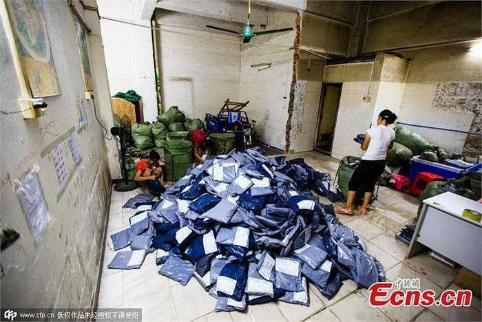 Một phụ nữ đang đóng gói sản phẩm để chuẩn bị giao cho khách hàng mua qua mạng. Nhà cô kinh doanh dịch vụ chuyển phát nhanh để đáp ứng nhu cầu chuyên chở hàng hóa rất lớn ở đây. 