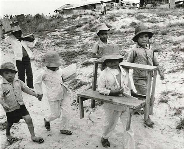 Các học sinh nhỏ bê bàn ghế đến lớp học ngoài trời của mình ở Quảng Trị, ngày 24/9/1973. Trường của các em đã bị phá hủy trong chiến sự năm 1972.