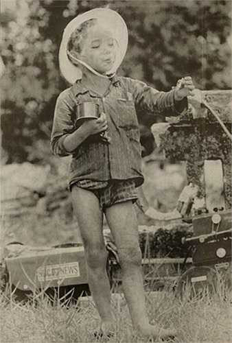 Một em bé tản cư tỏ ra rất mãn nguyện với một tay cầm hộp thực phẩm, tay kia cầm điếu thuốc do lính Mỹ đưa cho và miệng nhả khói thuần thục, ngày 1/5/1967.