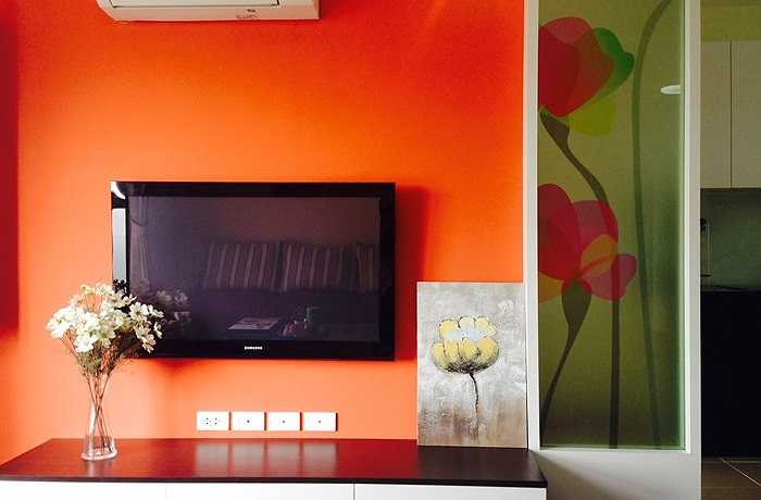 Một căn hộ diện tích nhỏ (80 m2) với 2 phòng ngủ, 1 phòng khách luôn khiến chủ nhân phải đau đầu nghĩ cách làm tăng diện tích lên. Chính vì thế phòng khách khéo léo đưa bức tranh kính vào làm không gian rộng ra và che khuất đi được một góc ở khu bếp. Cửa sổ kính lớn cũng làm phòng khách không bị kín lại và tạo được view cho căn phòng. Gam màu cam cũng tạo cảm giác sang trọng, ấm áp.