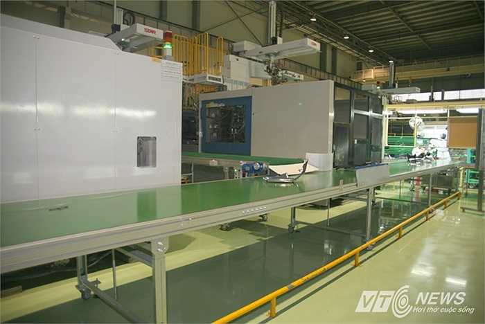 Trên băng tải, chi tiết bằng nhựa chạy đến nơi kiểm tra của kỹ thuật viên xưởng nhựa.