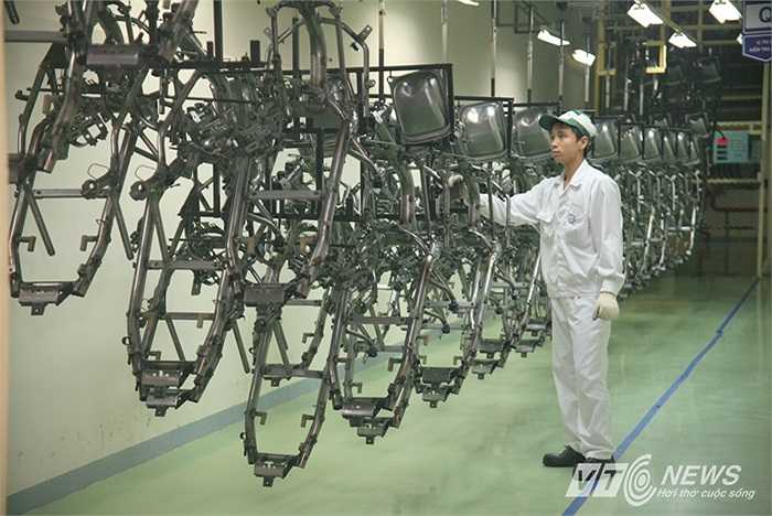 Khung xe được đưa lên băng tải treo xếp hàng trước khi vào buồng phun sơn, kỹ thuật viên tiếp tục kiểm tra các khung xe lần cuối.