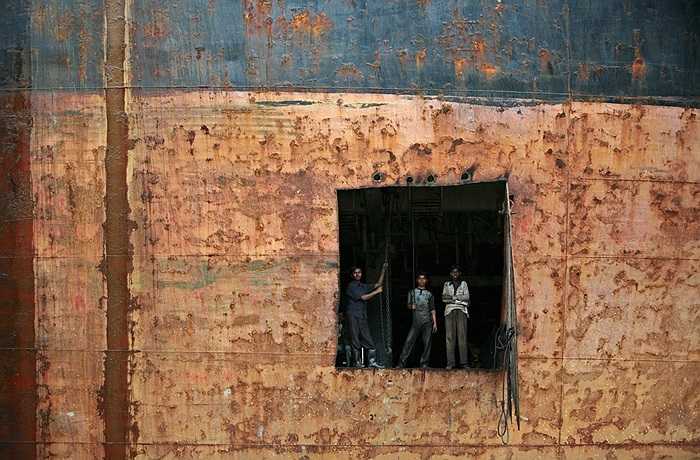 Những công nhân đứng cạnh một lỗ khoét trên thân tàu