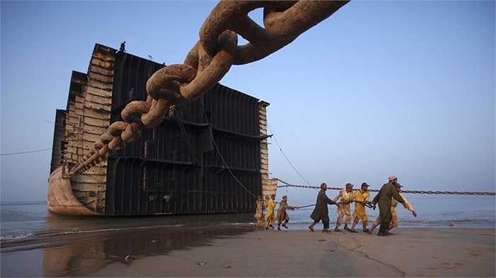 Những người lao động kéo dây xích khổng lồ để tách các phần đã cắt của xác con tàu