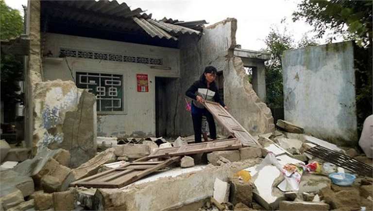 Bà Nguyễn Thị Lệ Thủy (45 tuổi, ở xóm 3, thôn Bình Thái) đang dọn dẹp những đống hoang tàn trên căn nhà bị sập của mình (Bình Định) - Ảnh: Tuổi trẻ