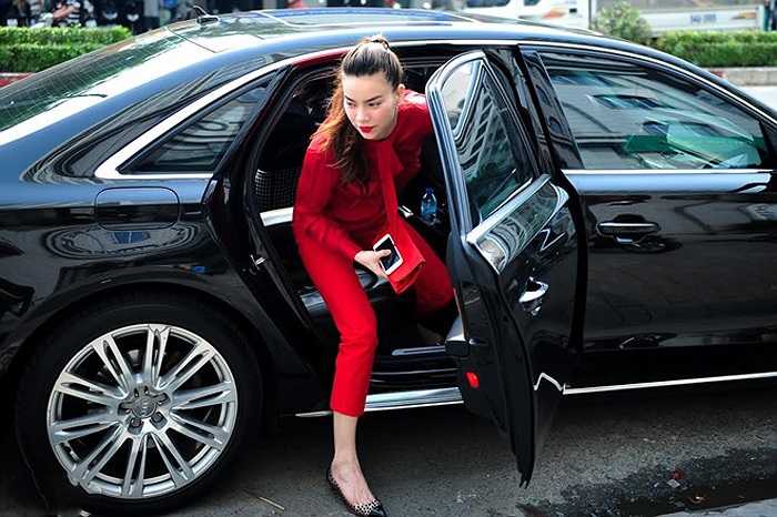 Hồ Ngọc Hà dùng bộ trang phục màu đỏ nổi bật bên cạnh chiếc xe hơi hạng sang màu đen.