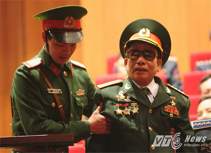 Một cựu chiến binh được chiến sĩ trẻ giúp đỡ vào ghế ngồi