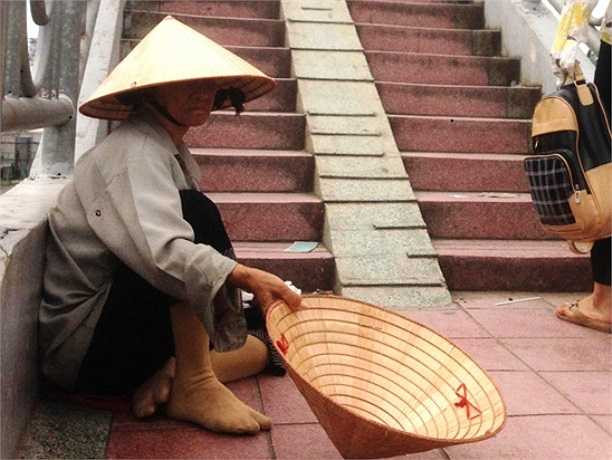 Một người già đóng khổ xin tiền người đi đường ở cầu bộ hành, Suối Tiên. (Ảnh Lê Hưng)