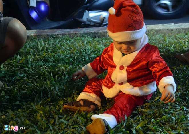 Ông già Noel nhí thoải mái vui chơi giữa bãi cỏ ở trung tâm thành phố.