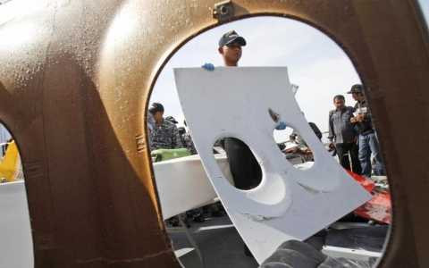 Nhân viên tham gia tìm kiếm trên tàu Hải quân KRI Bung Tomo giơ mảnh cửa sổ máy bay QZ8501 vừa được tìm thấy