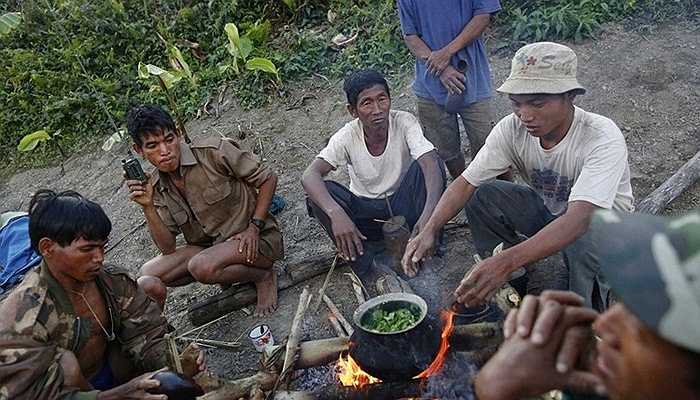 Các thành viên trong tộc người đang nấu một món ăn với rau cải và thuốc phiện, họ cho rằng thuốc phiện sẽ làm món ăn có vị ngon hơn. Trong ảnh cũng có thể thấy một người đàn ông đang sử dụng bộ đàm vì họ không dùng điện thoại.