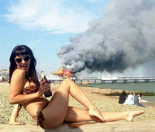 Vui đùa khi thấy tai nạn: Bên cạnh những kiểu chụp ảnh với quan tài, xác chết... tạo dáng khi trông thấy người khác gặp tai nạn, trước đám cháy cũng được đánh giá là rất phản cảm. Mặc dù vậy, các tấm hình dạng này vẫn thường xuyên được giới trẻ chia sẻ trên mạng. Có thể thấy như Louisa Foley (cô gái trong ảnh). Louisa tự tin mặc bikini uốn éo, thể hiện rõ sự phấn khích dù biết đằng sau mình là đám cháy rất lớn tại bến tàu Eastbourne (Anh). (Ảnh: Daily Mail)