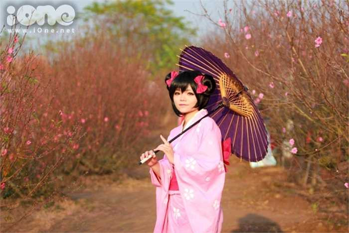 Một bạn nữ trong trang phục kimono tạo dáng bên hoa đào.