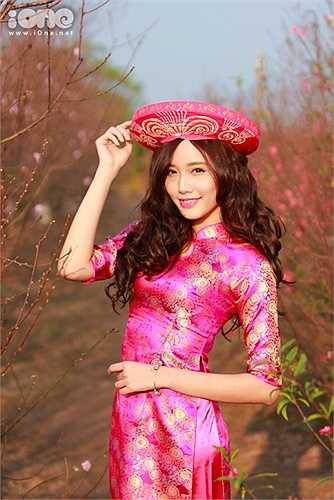 Cô nàng lựa chọn trang phục áo dài màu hồng khoe sắc cùng hoa đào.