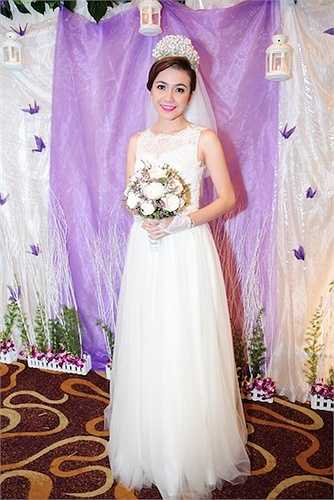 Khác với vẻ truyền thống và duyên dáng trong lễ đón dâu tại nhà trai vào buổi sáng, cô dâu Ái Châu lộng lẫy trong mẫu đầm cưới gam màu trắng trong trẻo. Thiết kế khá gọn gàng với độ bồng vừa phải, thân áo cũng được may kín đáo và tối giản, phù hợp tính cách nhẹ nhàng của á hậu Phụ nữ Việt Nam 2005. 