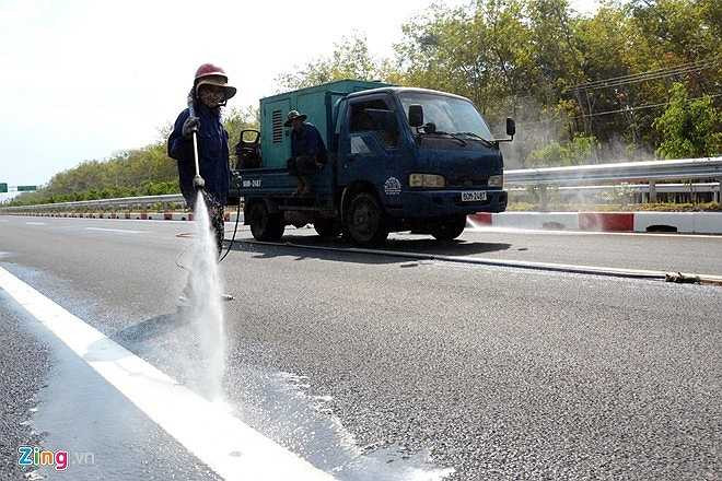 Công nhân dùng nước rửa sạch dải phân cách, vạch phân làn bị dính bẩn trong quá trình thi công để đảm bảo tuyến đường được sạch sẽ trước ngày thông xe toàn bộ 55 km từ TP HCM - Đồng Nai.