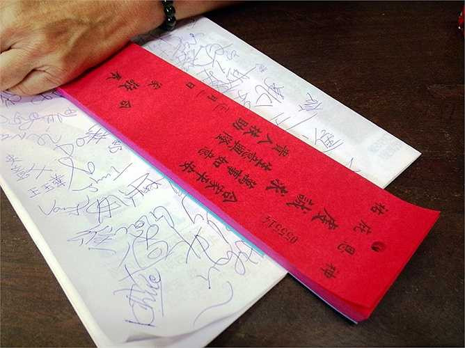 Giấy đỏ viết chữ Hoa bằng mực Tàu, ghi rõ tên họ người mong muốn cầu an, cầu siêu. (Ảnh: Phan Cường) 