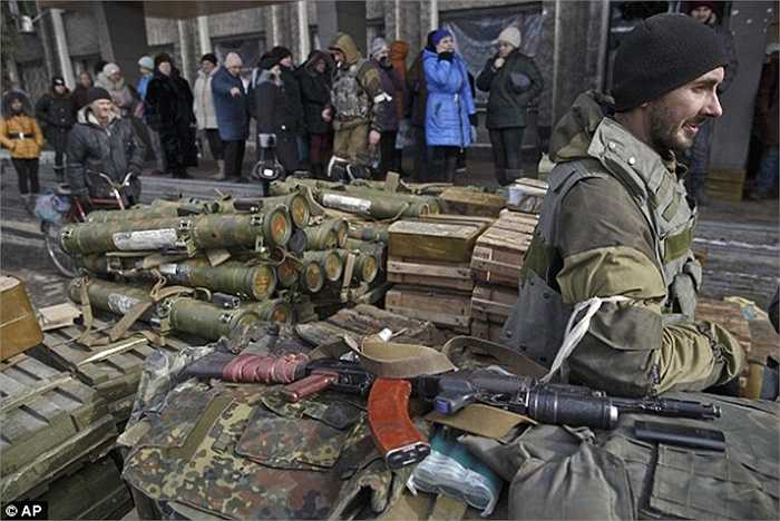Cư dân địa phương Debaltseve đứng cạnh một chiến binh ly khai đang canh giữ vũ khí