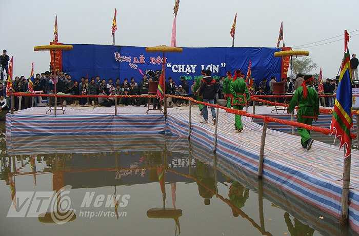 Tại ao trước đình, thanh niên trong làng đã dựng lên một sân khấu nổi khá hoành tráng. Các “ông lợn” nằm trong những chiếc cũi rất đẹp, được khiêng đến sân đình. Vị chủ tế vào đình thắp hương khấn vái thông báo với các vị thần linh chuẩn bị lễ mổ lợn tế thần.