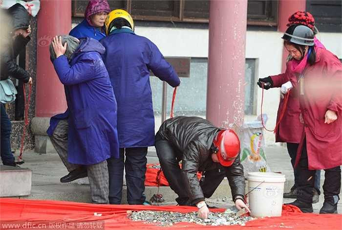 Đầu năm mới, lượng khách hành hương đổ về ngôi đền thờ thần Tài ở Vũ Hán (Trung Quốc) rất đông thêm vào đó là tục ném tiền xu lên mái nhà khiến số lượng tiền xu rơi xuống lên đến nhiều kg
