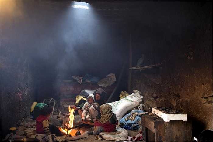 Bà mẹ sưởi ấm cho đứa con quanh đống lửa trong ngôi làng Tilmi, Morocco