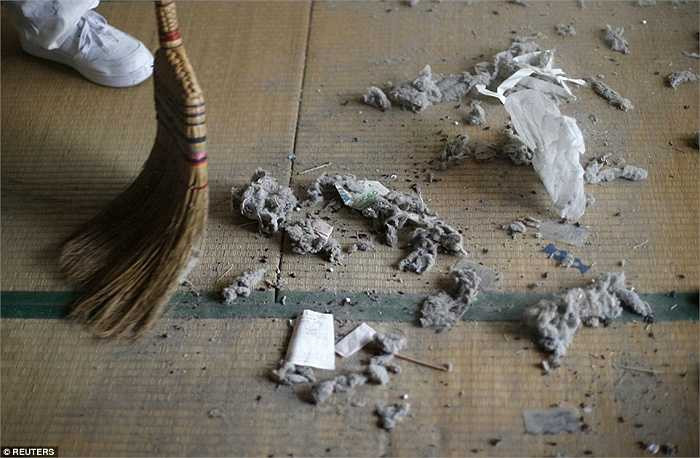 Một nhân viên dọn rác đang quét dọn sàn nhà.