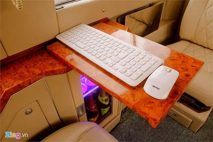 Bàn phím và chuột không dây được đặt trên bàn. Chủ nhân có thể giải quyết công việc hoặc điều khiển thiết bị giải trí khi đang di chuyển. Bàn phím được kết nối với máy tính Mac mini đặt dưới tủ đựng ly.