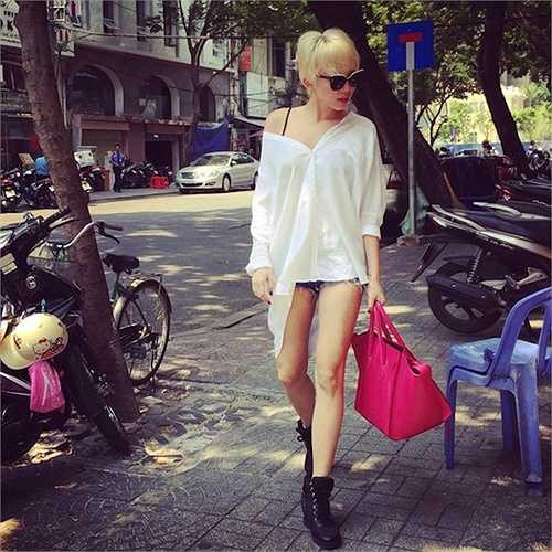 Tóc Tiên nổi bật trên phố với sơ mi trắng kéo lệch vai và sooc ngắn. 