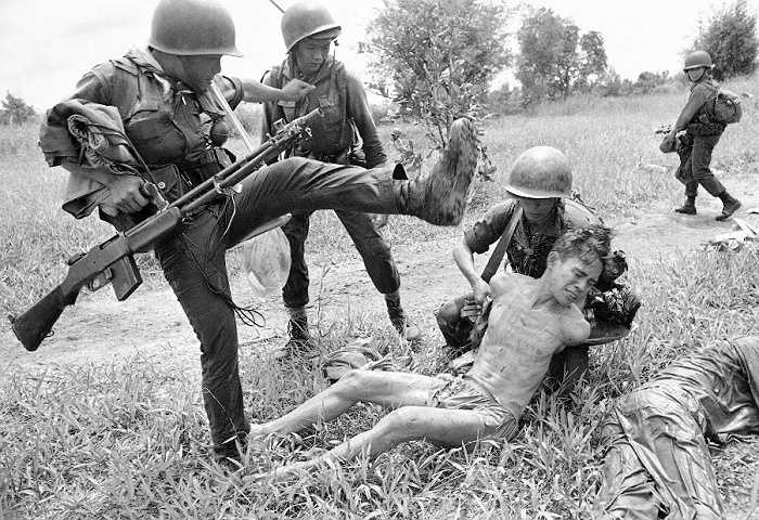Lực lượng VNCH đánh một người bị tình nghi là quân Giải phóng trong tháng 10/1965. Ông là một trong 15 người bị bắt sau trận càn. Ảnh: AP
