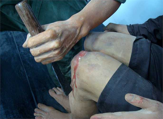 Bọn cai ngục dùng chiếc đục bằng sắt, thứ mà thợ mộc dùng, đặt vào đầu gối, rồi dùng búa gỗ gõ mạnh, khiến đục xuyên vào chân, đánh bật xương bánh chè ra ngoài. Cách tra tấn này khiến nhiều tù nhân bại liệt suốt đời.