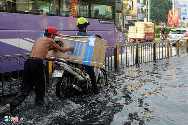 Chị Hoàng Yến (quê Gia Lai) đi giao hàng đến đoạn đường ngập thì xe chết máy. Người dân ở khu vực chạy đến đẩy giúp xe người phụ nữ đến chỗ khô ráo.