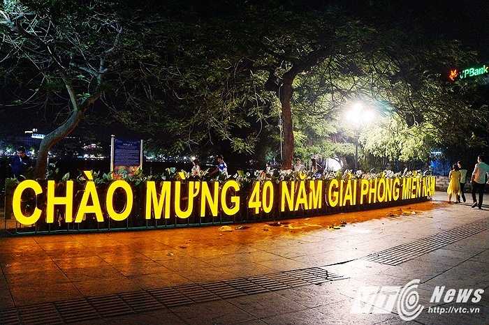 Đèn biểu ngữ 'Chào mừng 40 năm giải phóng miền Nam' màu vàng nổi bật được đặt ngay tại trung tâm của bờ Hồ Hoàn Kiếm.