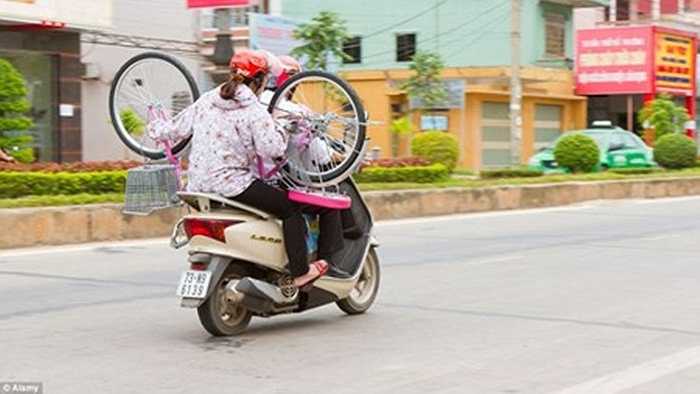 Một người phụ nữ chở theo cả chiếc xe đạp khi ngồi sau xe máy