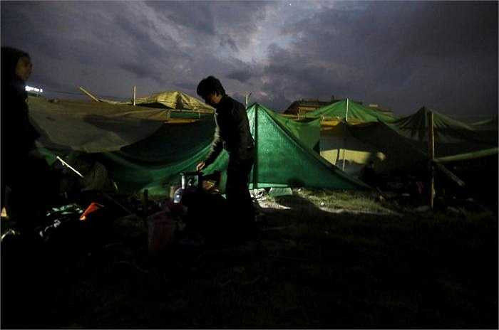 Một cậu bé chuẩn bị nấu thức ăn tại khu lều tạm nằm trên bãi đất trống, cuộc sống đang rất khó khăn với người dân Nepal.