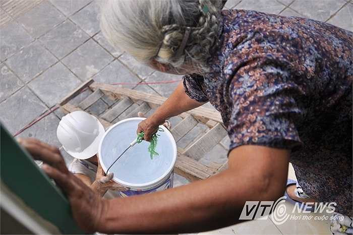 Nhà bà Ngoan cao hơn mặt được trên 1 mét. Trong ảnh bà Ngoan từ tầng trệt ngôi nhà đưa nước cho một công nhân ở dưới vỉa hè.