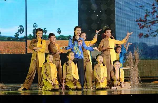 Sau đó, các bé nhỏ trong team The Voice Kids xuất hiện cùng cô giáo Cẩm Ly và 2 cô con gái xinh xắn của mình tham gia trong điệu múa Lâm Thol Trà Vinh rộn ràng và trình diễn bài Gánh lúa.