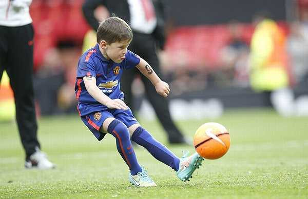 Kai, con trai đầu lòng của chàng Shrek, hồn nhiên trổ tài chơi bóng trên sân. Cậu nhóc 5 tuổi rưỡi gây chú ý với hình vẽ bằng mực in dễ xóa trên cánh tay trái.