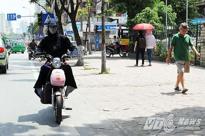 Người thì mặc áo chống nắng, người thì dùng ô để chống chọi với cái nắng gay gắt của trưa hè.