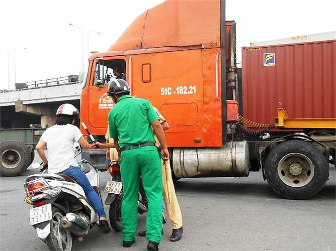 Một cô gái hốt hoảng té ngã khi phát hiện xe container di chuyển trước mặt.