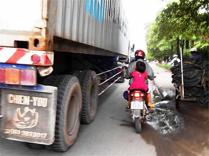 Cha chở con không đội nón bảo hiểm di chuyển trong khu vực nguy hiểm.