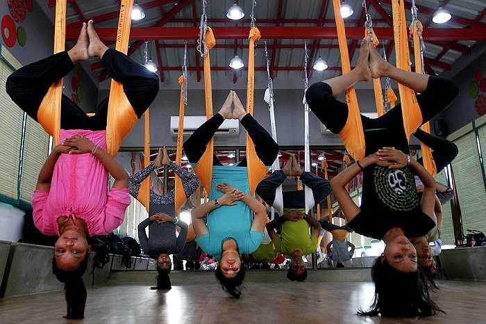 Một số người tập yoga trong tư thế treo ngược, lơ lửng ở Ahmadabad, Ấn Độ