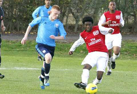 Cầu thủ nhí của Arsenal (phải) vẫn thi đấu với giày tất