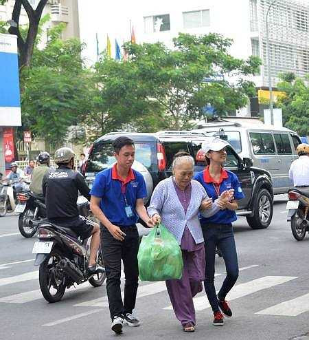 Tình nguyện viên dẫn một cụ già qua đường - Ảnh: Internet